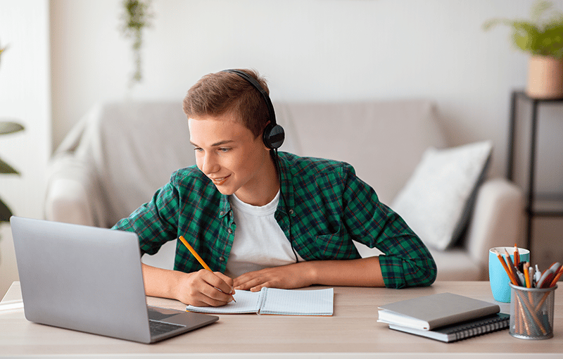 joyful-teen-guy-writing-at-notebook-and-looking-at-2025-03-18-17-34-38-utc